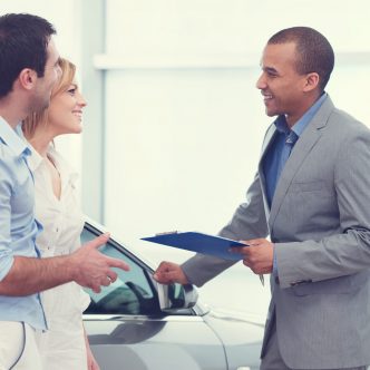 Un jeune couple discute avec un vendeur conseiller de voiture